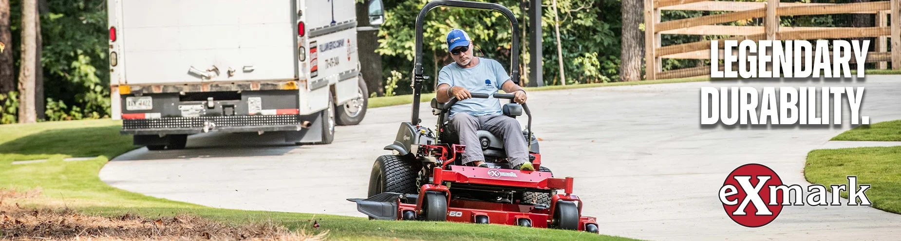 Man operating a red Exmark commercial zero-turn mower along a driveway with a work truck in the background and the words “Legendary Durability” displayed on the right